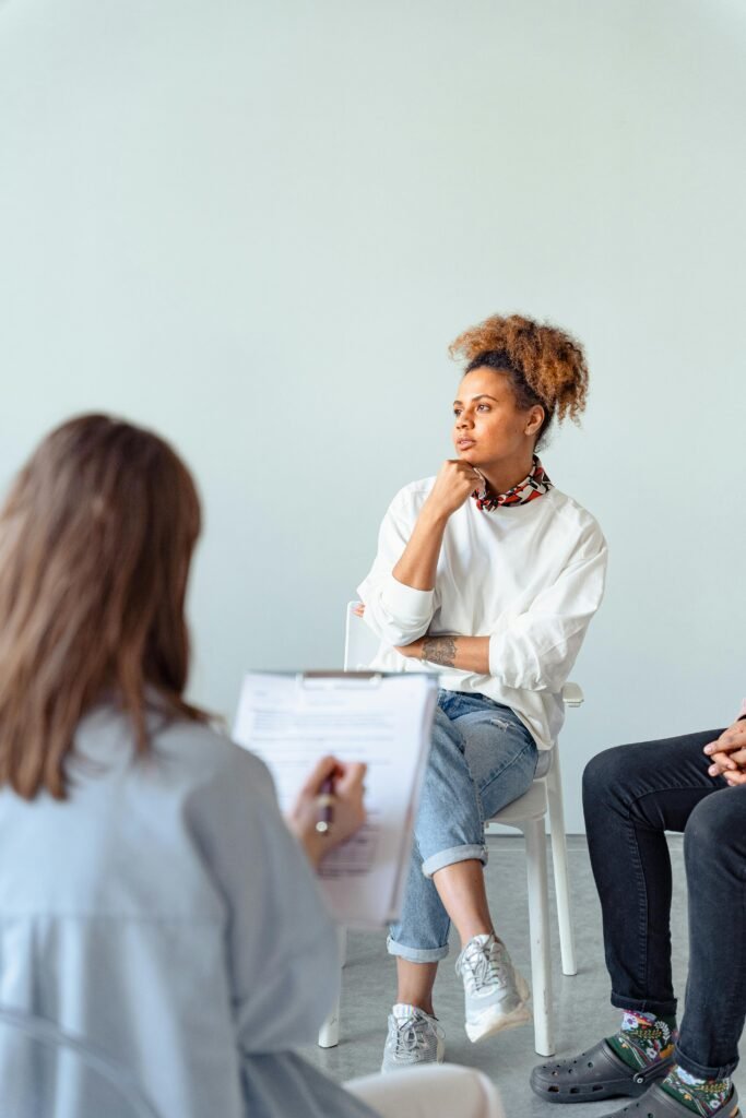 A thoughtful woman attending a counseling session with a professional indoors.